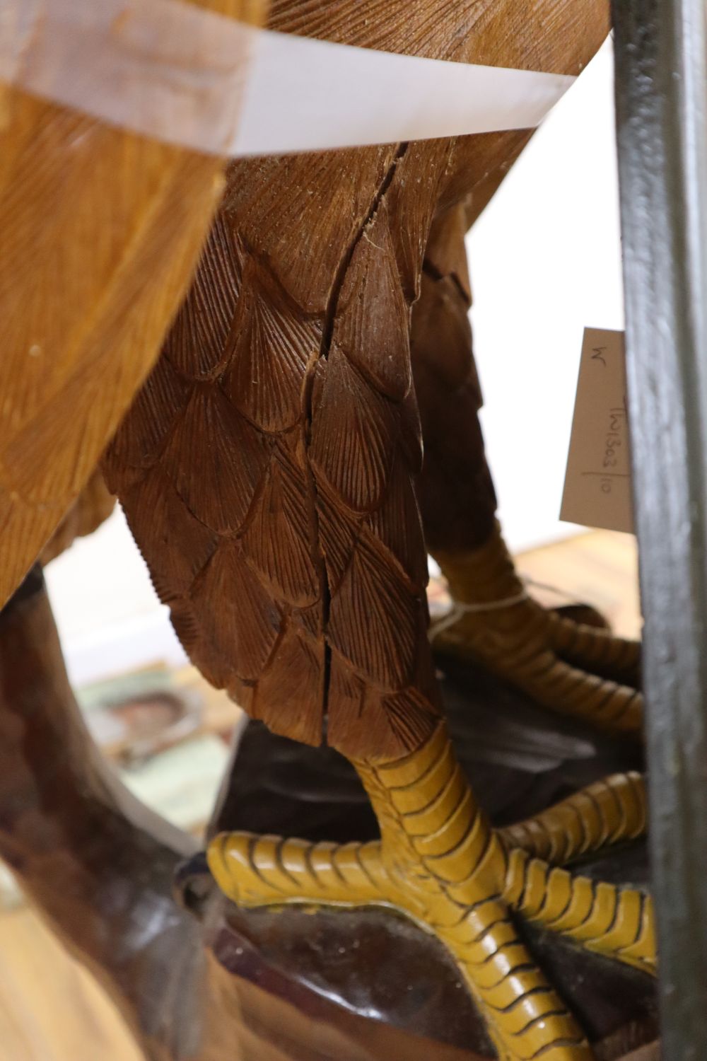 A carved and painted wood model of a Bald Eagle perched on a tree stump and a carved and painted wood hanging sign